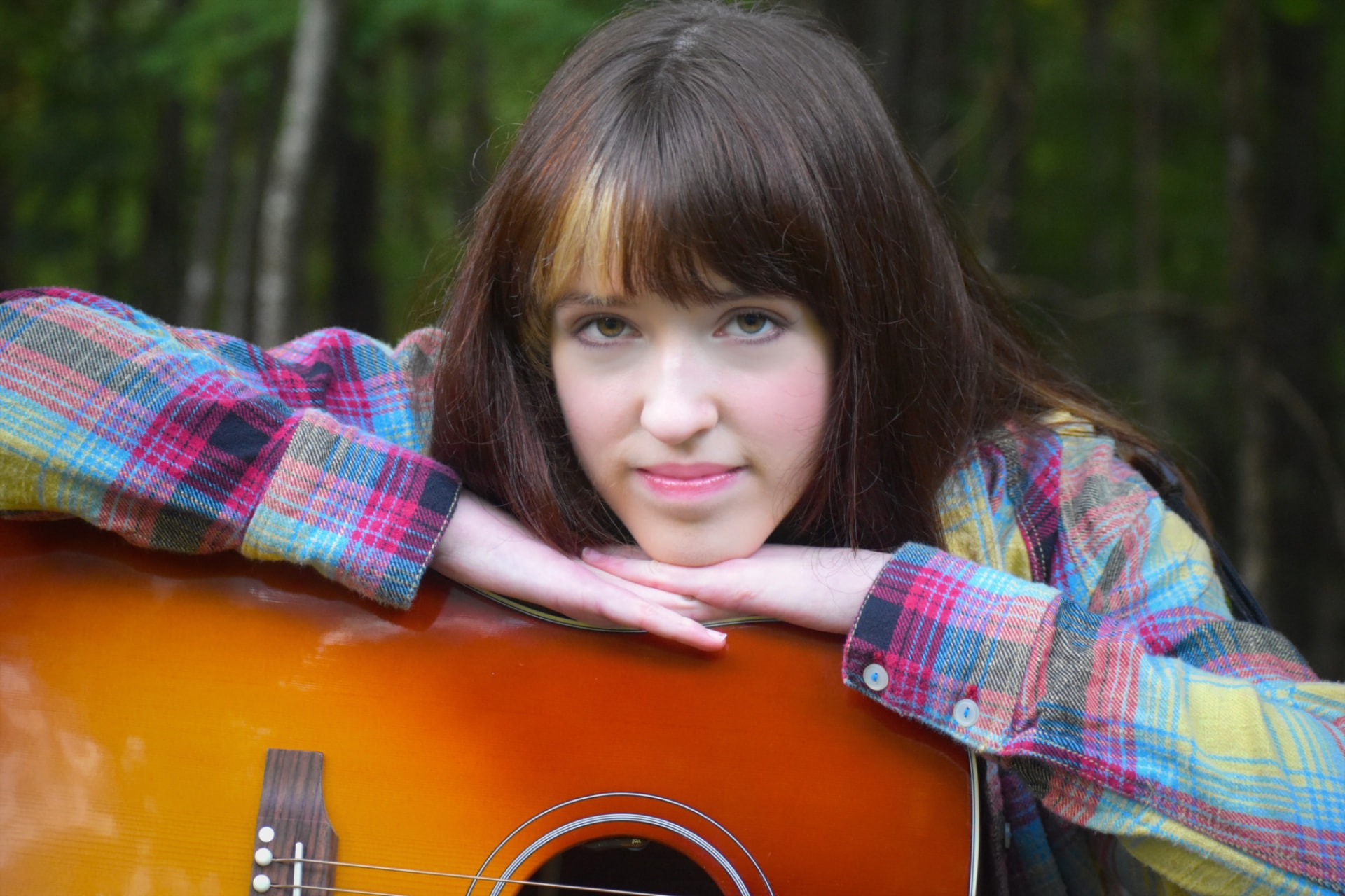 Josette Seraphine resting her chin on her acoustic guitar